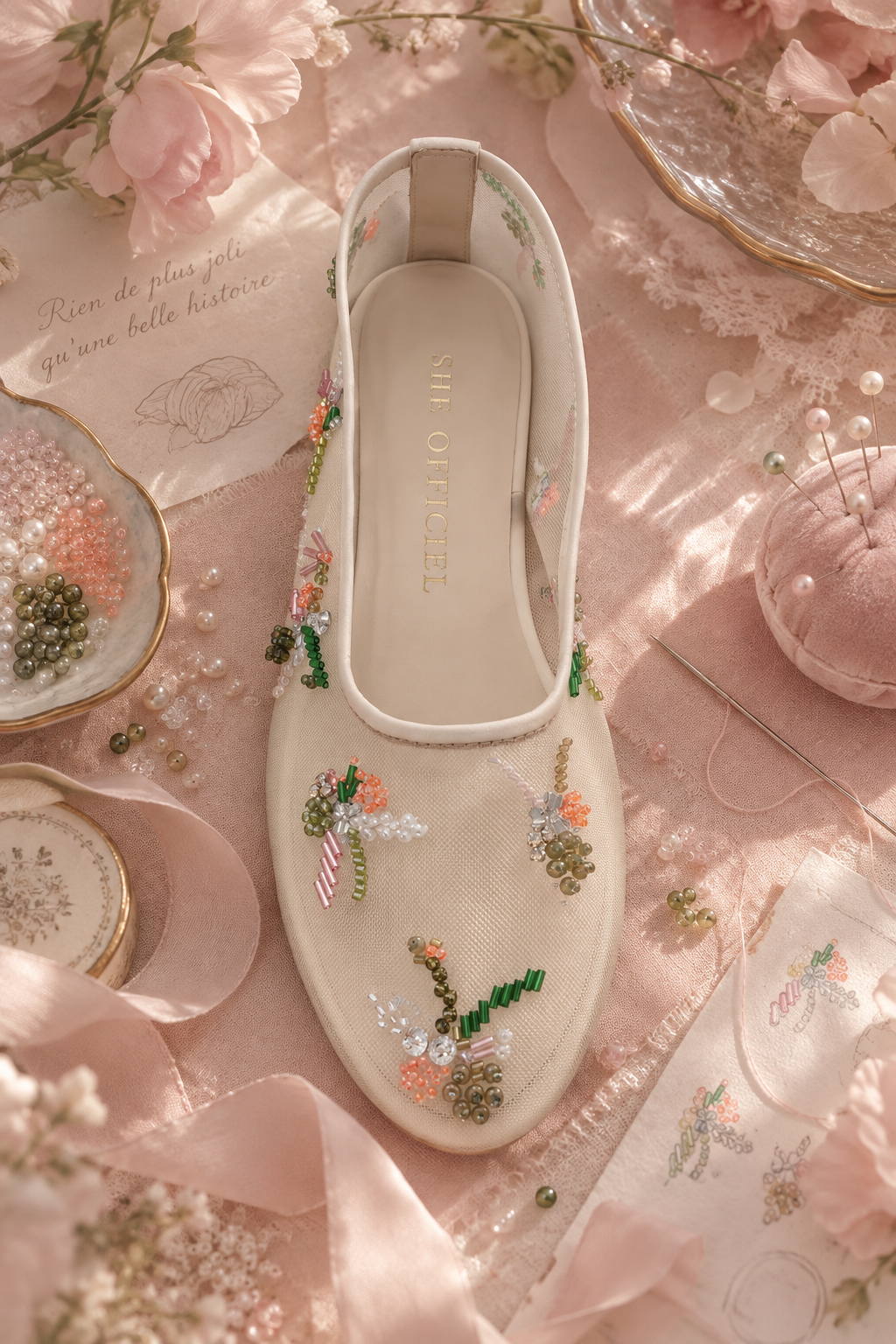 Hand embroidered ballerina mesh flats surrounded in a pink inspired background with beads and needle and thread for that behind the scenes look