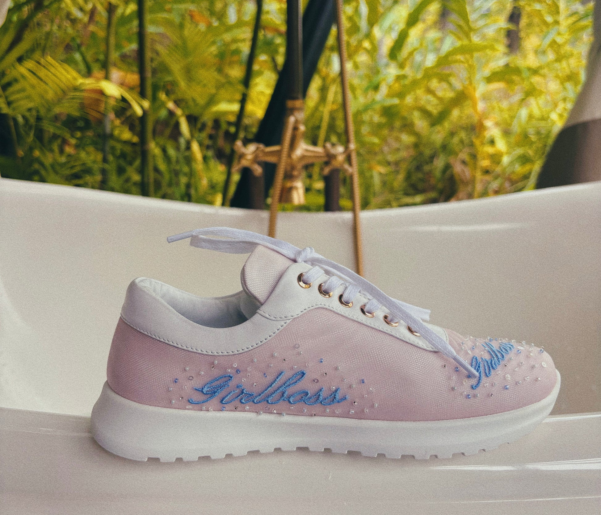 Pink and white sneaker with 'Bella Bliss' branding on a blurred natural background